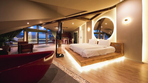 A modern bedroom with a large bed, wooden beams, and a circular mirror. - Tare Houses Hotel (Istanbul)