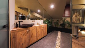 A modern bathroom with a wooden vanity, a large mirror, and a stone pathway leading to a seating area. - Tare Houses Hotel (Istanbul)