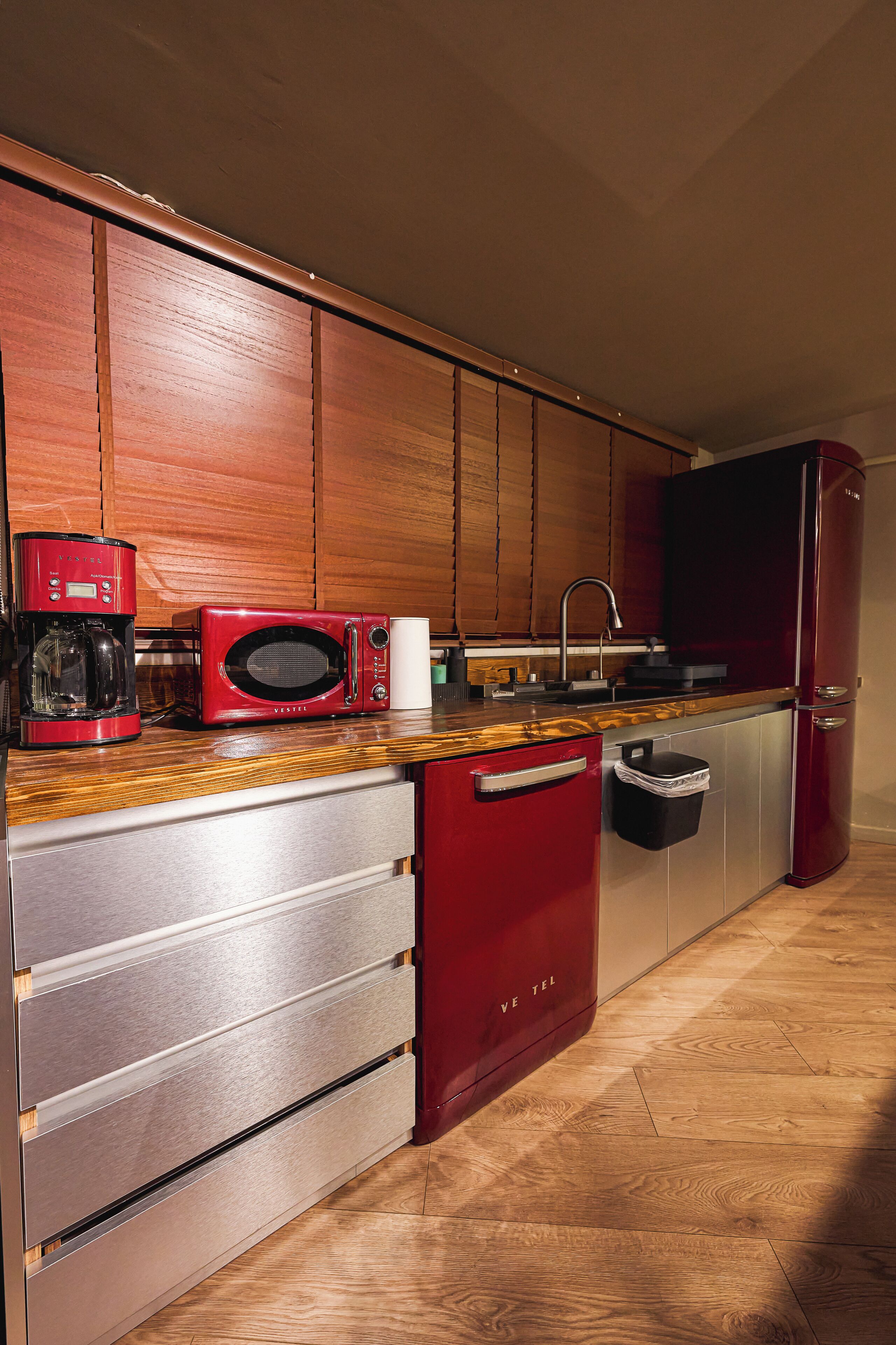 A compact kitchen with wooden cabinets, a microwave, a coffee maker, and a refrigerator.
