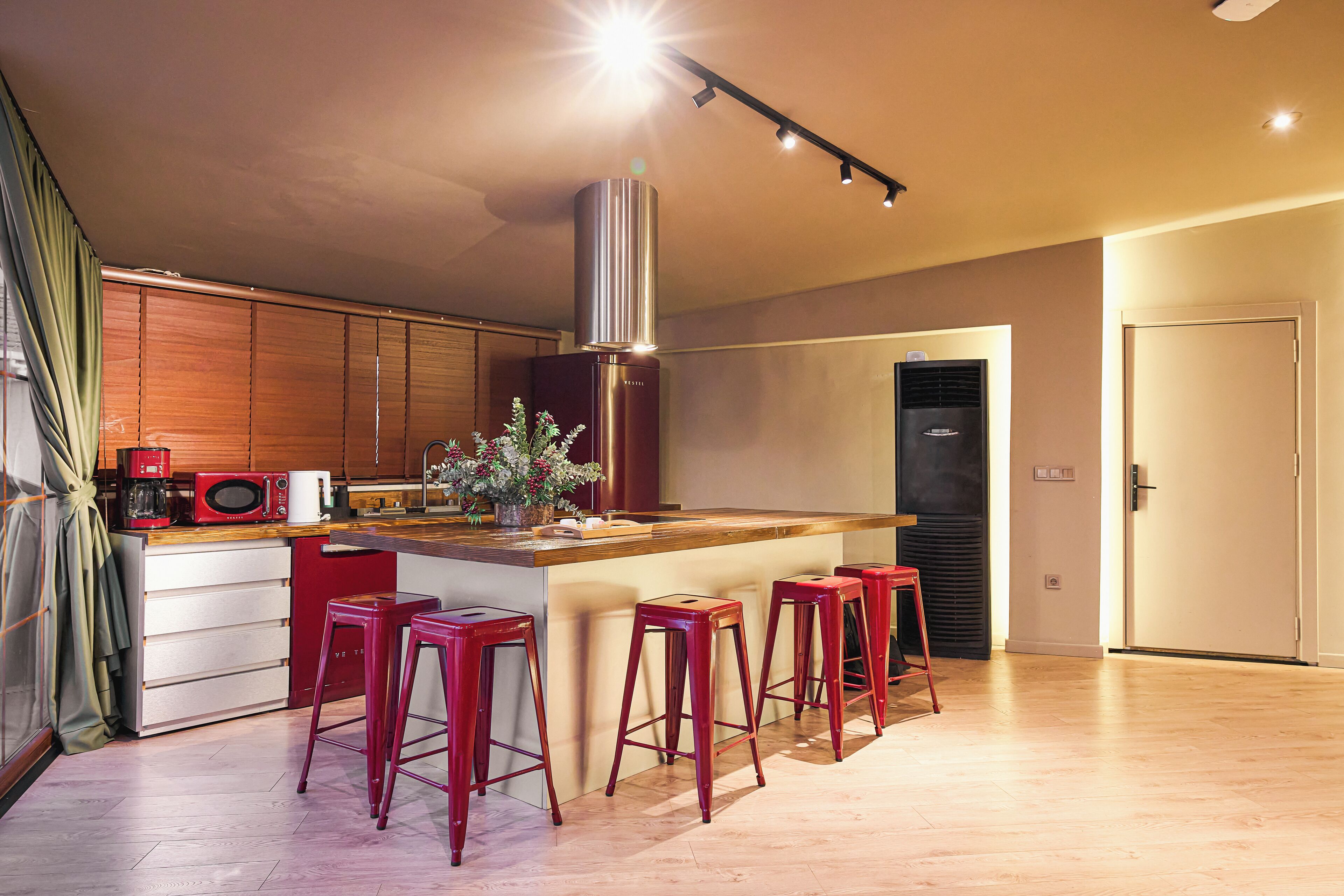 A modern kitchen with a central island, bar stools, a microwave, and a stainless steel range hood.