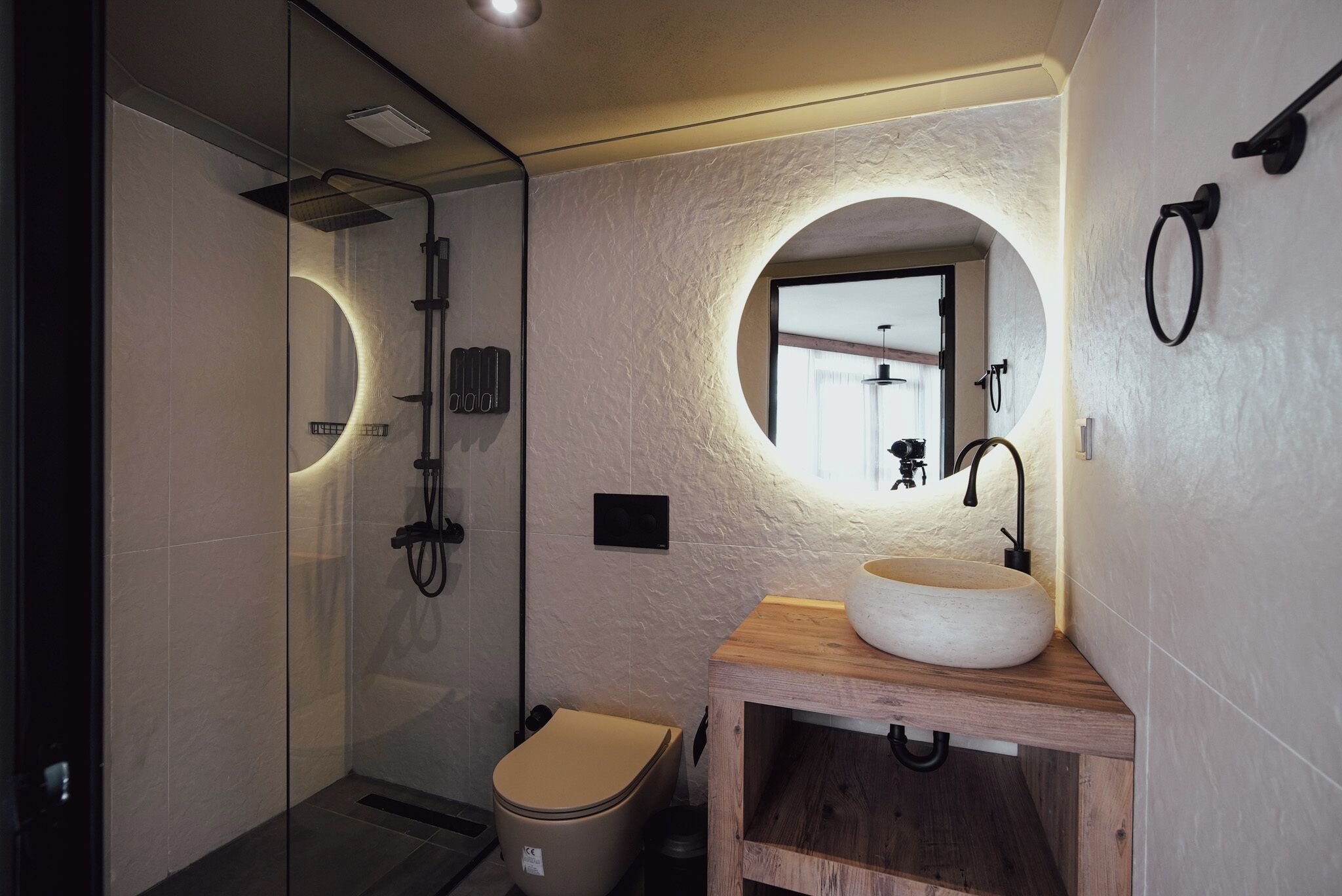 A modern bathroom with a glass shower enclosure, a wooden vanity with a large sink, and a toilet.