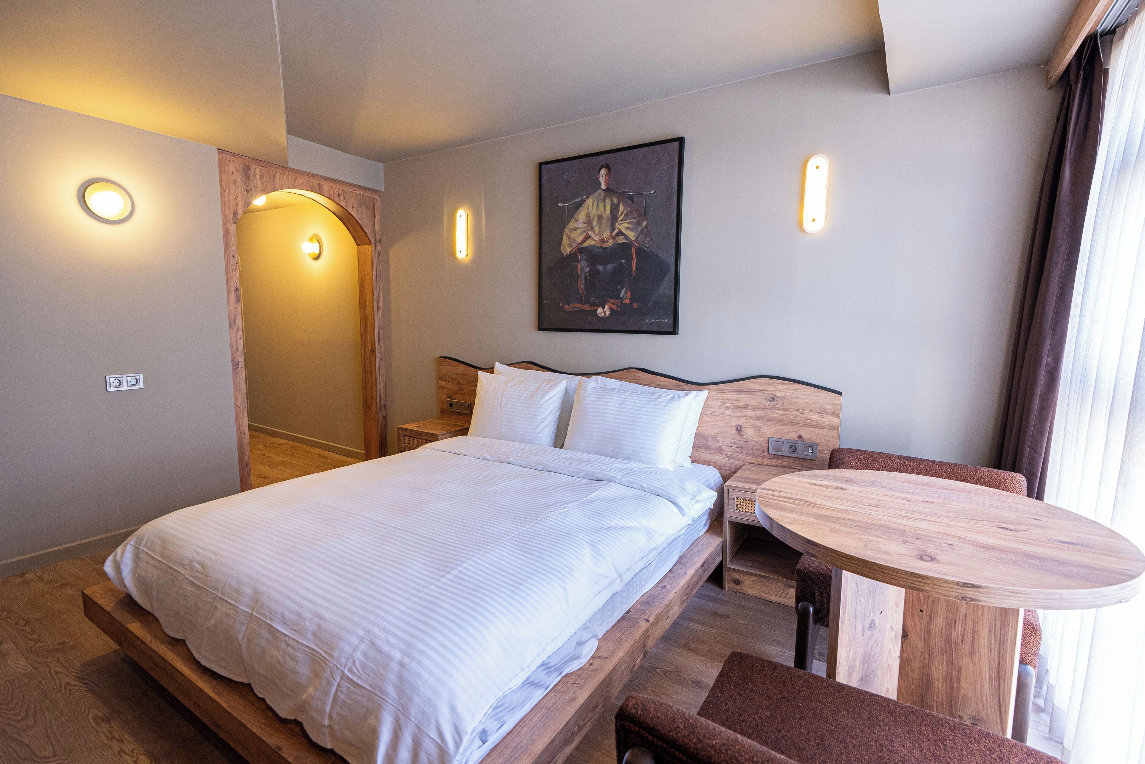 Makuuhuoneessa on sänky, yöpöytä ja pieni puinen pöytä.