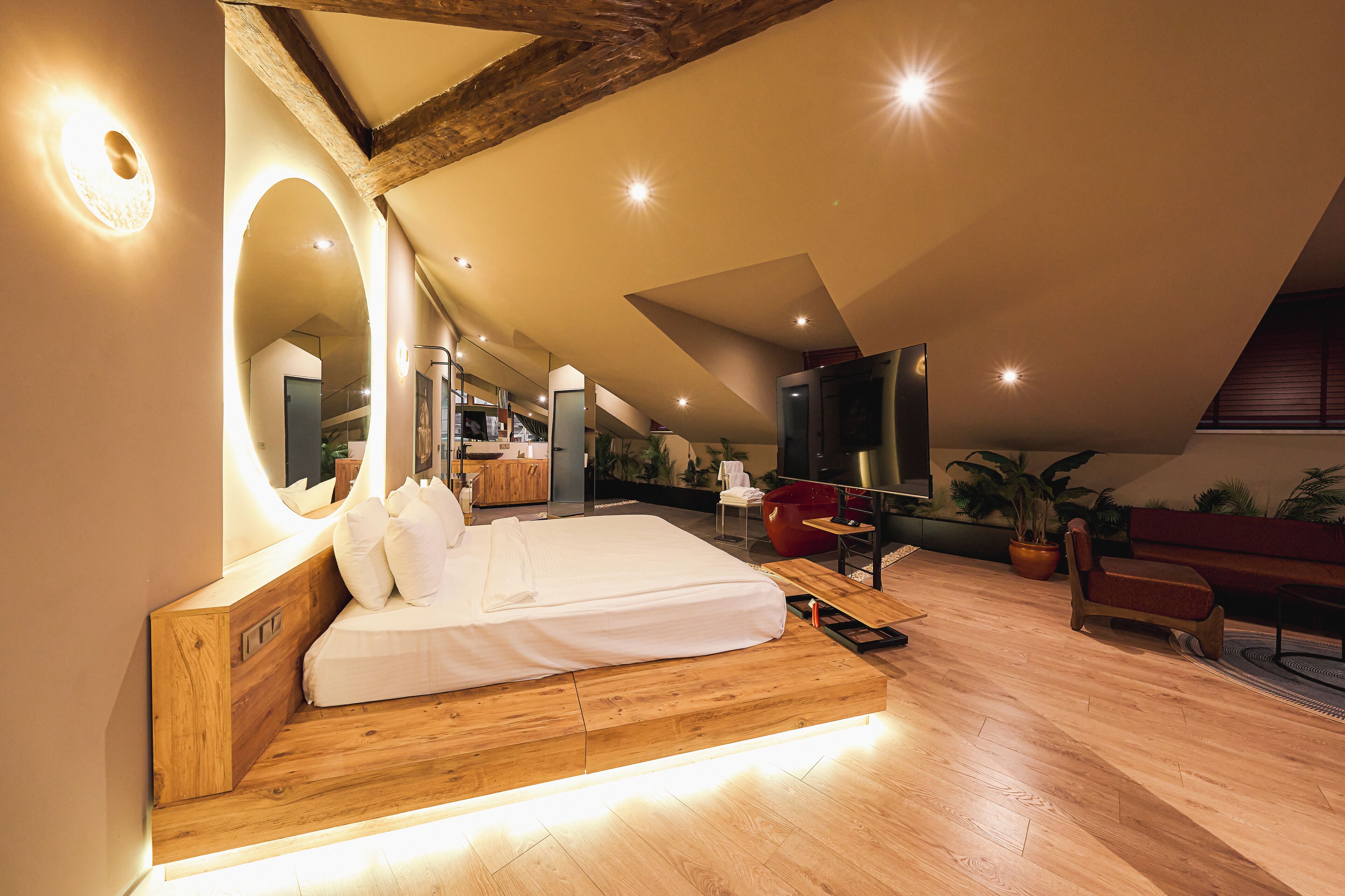 A bedroom with a wooden bed, a large mirror, and a ceiling with exposed beams.