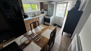 Une cuisine compacte avec un coin repas, comprenant un réfrigérateur, une cuisinière, un four à micro-ondes et un évier.