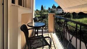 A balcony with a table and chairs, a view of a distant building, and a clear sky. - Elli Cozy House (Corfu)