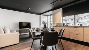 A modern living room with a sofa, dining table, chairs, and a TV.