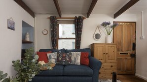 Ein gemütliches Wohnzimmer mit einem blauen Sofa, einer Holzkommode und einer Weinflasche auf einem Tisch.