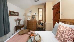 Ein Schlafzimmer mit Bett, Schminktisch, Spiegel und einer Holztür.