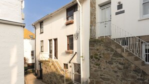 Eine enge Straße mit einem weißen Gebäude, das eine Steintreppe und ein Metallgeländer zeigt.