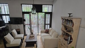 Un salon avec un canapé, une table basse, un téléviseur et une bibliothèque.
