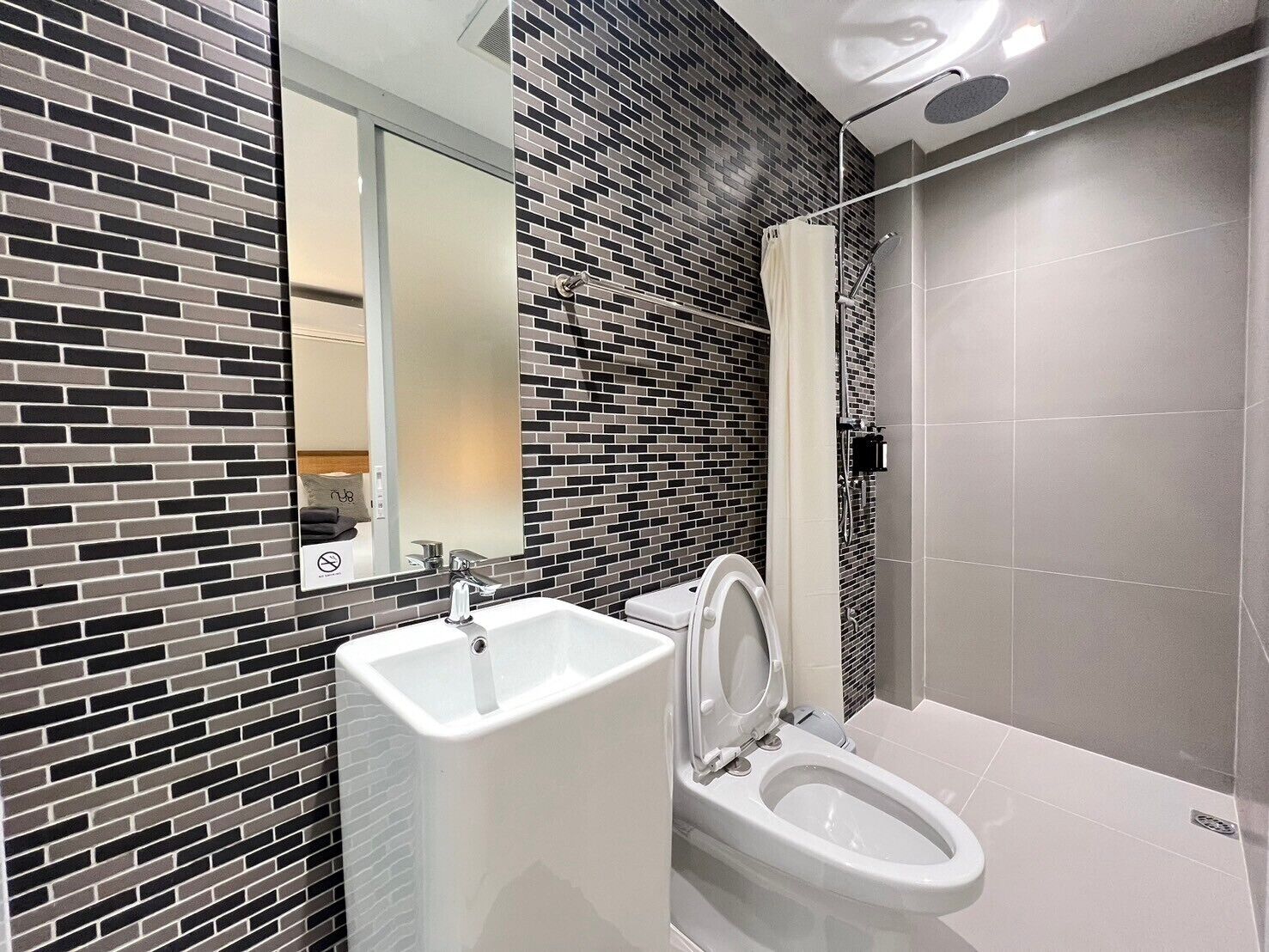 A modern bathroom with a white sink, a toilet, and a shower area.