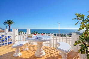 Enjoy a serene ocean view from this patio with a round table and two comfortable chairs.