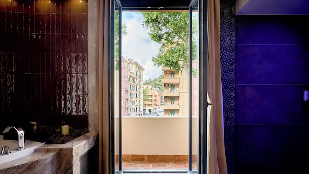 A bathroom with a marble sink, a bathtub, and a view of buildings through a glass door.