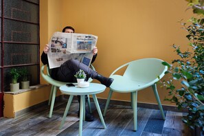 A person sitting on a chair reading a newspaper. - Mamaco Roma (Rome)