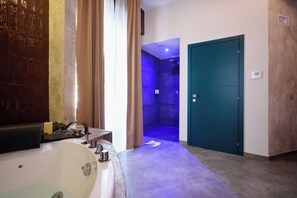 A modern bathroom with a large bathtub, a shower area with blue lighting, and a teal door. - Mamaco Roma (Rome)