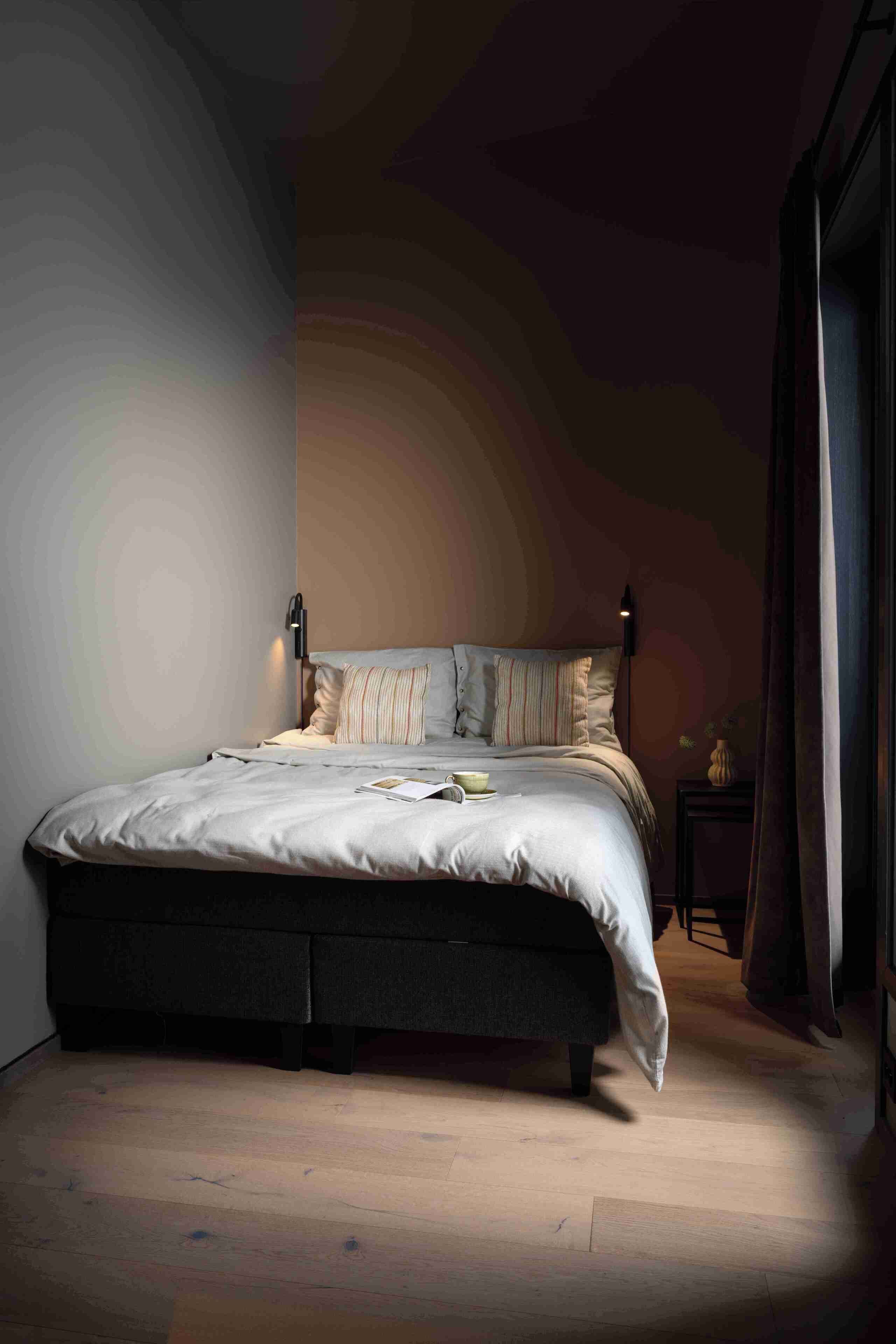 A bedroom with a bed, bedside lamps, and a nightstand.