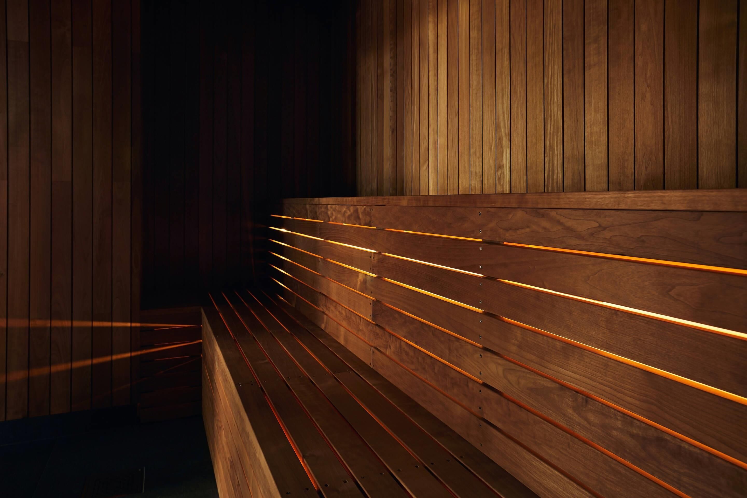 Um banco de madeira com linhas iluminadas na parte de trás em um ambiente com pouca luz.