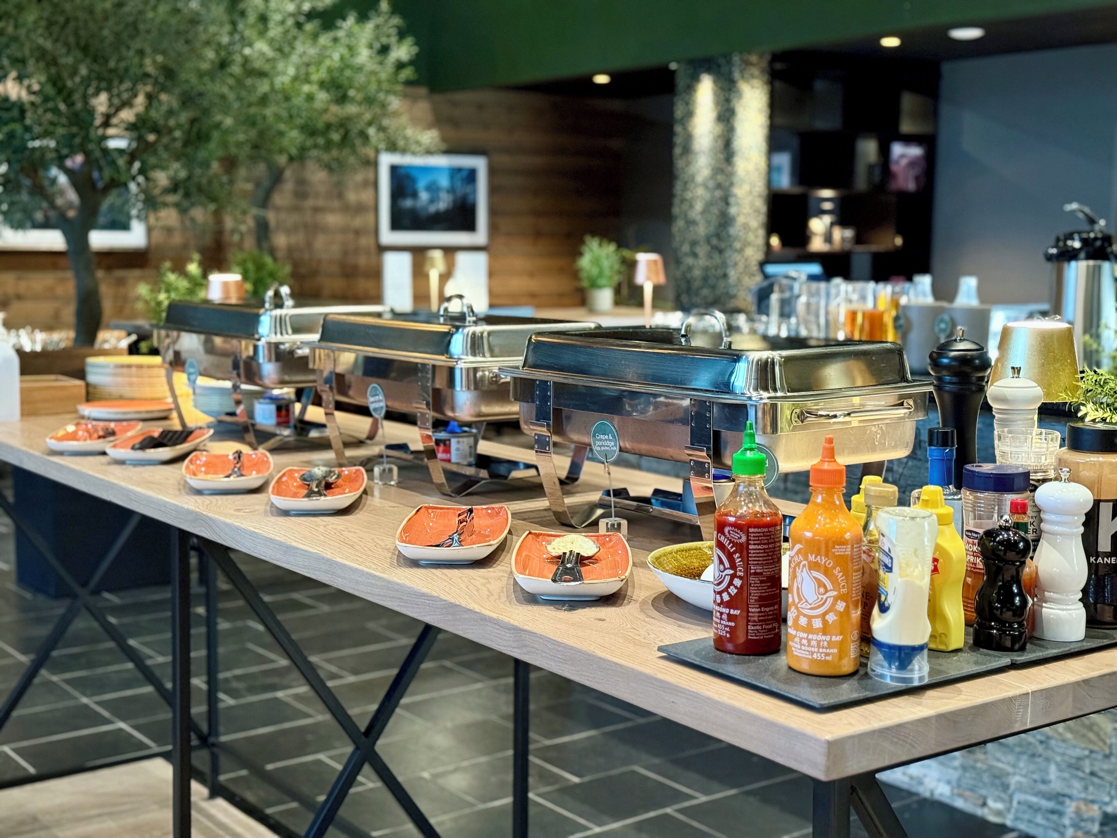 A buffet setup with multiple self-service stations, a variety of condiments, and a coffee machine.