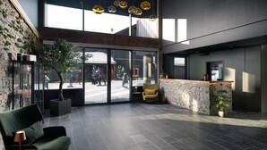 A modern lobby with a stone wall, a reception desk, and a seating area with a sofa and a chair. - Riddergaarden Hotel & Mountain Lodge, Beitostølen (Øystre Slidre)