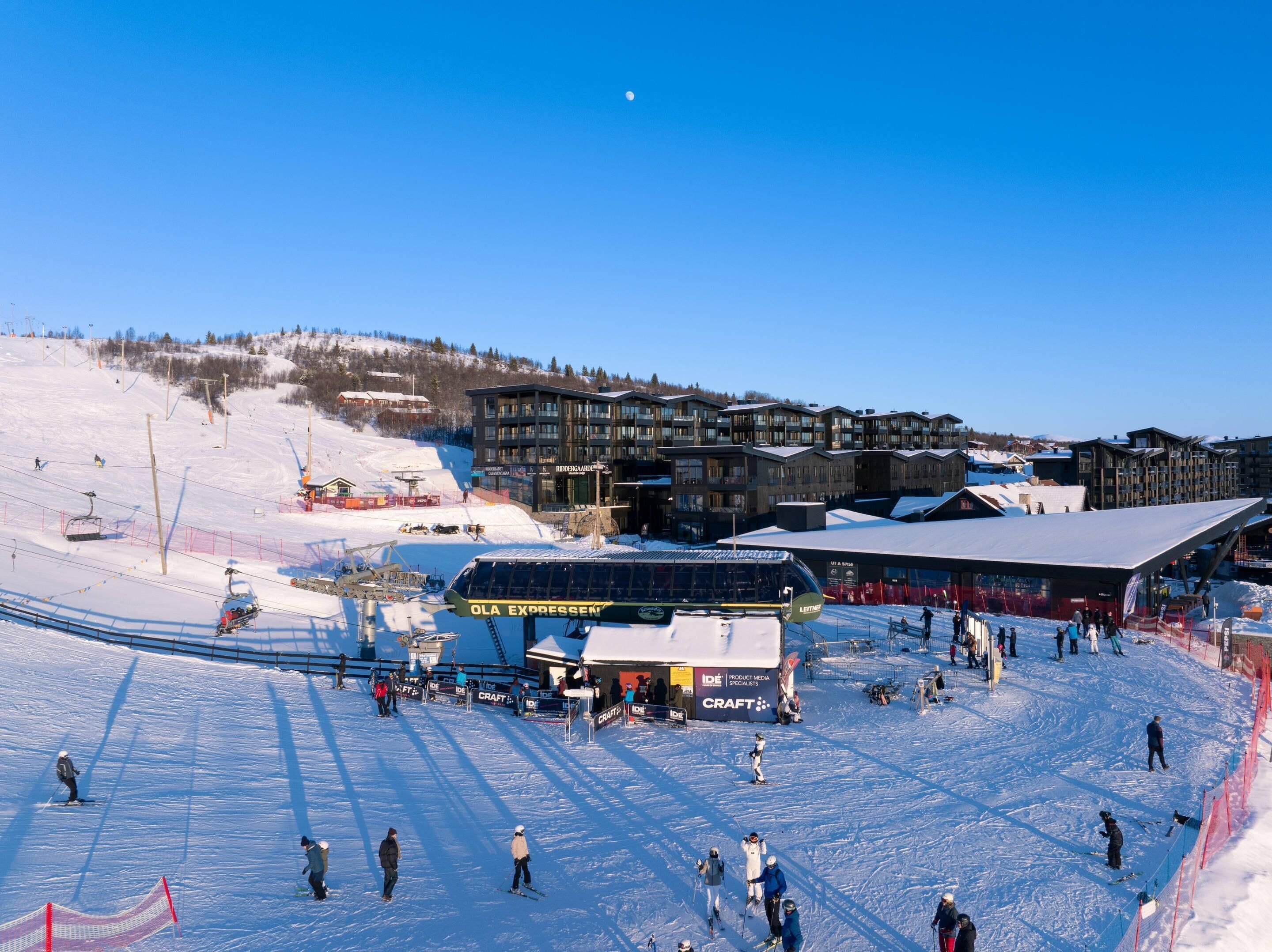 Un centro de esquí con telesilla, edificios y una ladera cubierta de nieve.