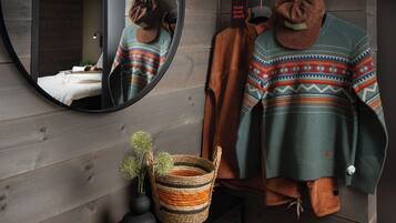 Une salle de bain moderne avec un mur en bois, un miroir rond, un porte-serviettes et une petite plante posée sur une console.
