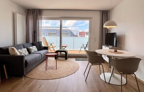 Uma sala de estar moderna com sofá, cadeiras, mesa de jantar e televisão.