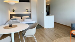 A modern hotel room with a bed, bedside tables, a desk, and a chair. - Kampstraße; Wohnung 20 (Norderney)