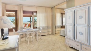 A hotel room with a dining area, a large wardrobe, and a view of the beach. - Residence with private beach in Bosa Marina (Bosa)