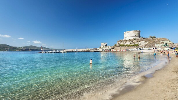 A coastal area with clear water, a sandy beach, and a historic fort on a hill. - Residence with private beach in Bosa Marina (Bosa)