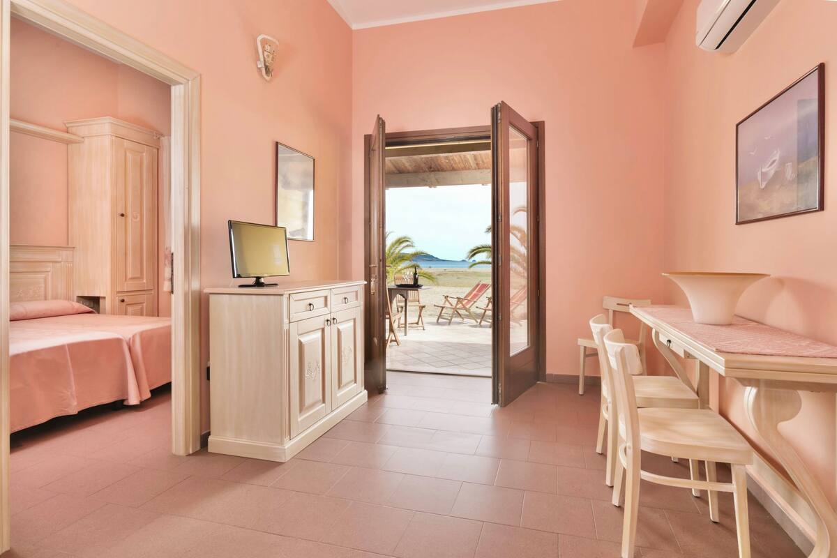 A room with a bed, a desk, and a view of the beach.