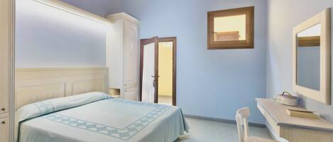 A bedroom with a bed, a desk, a chair, a wardrobe, and a window.