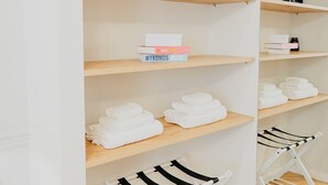 A neatly organized closet with wooden shelves, folded towels, and a white drying rack. - La clè de la maison (Naples)