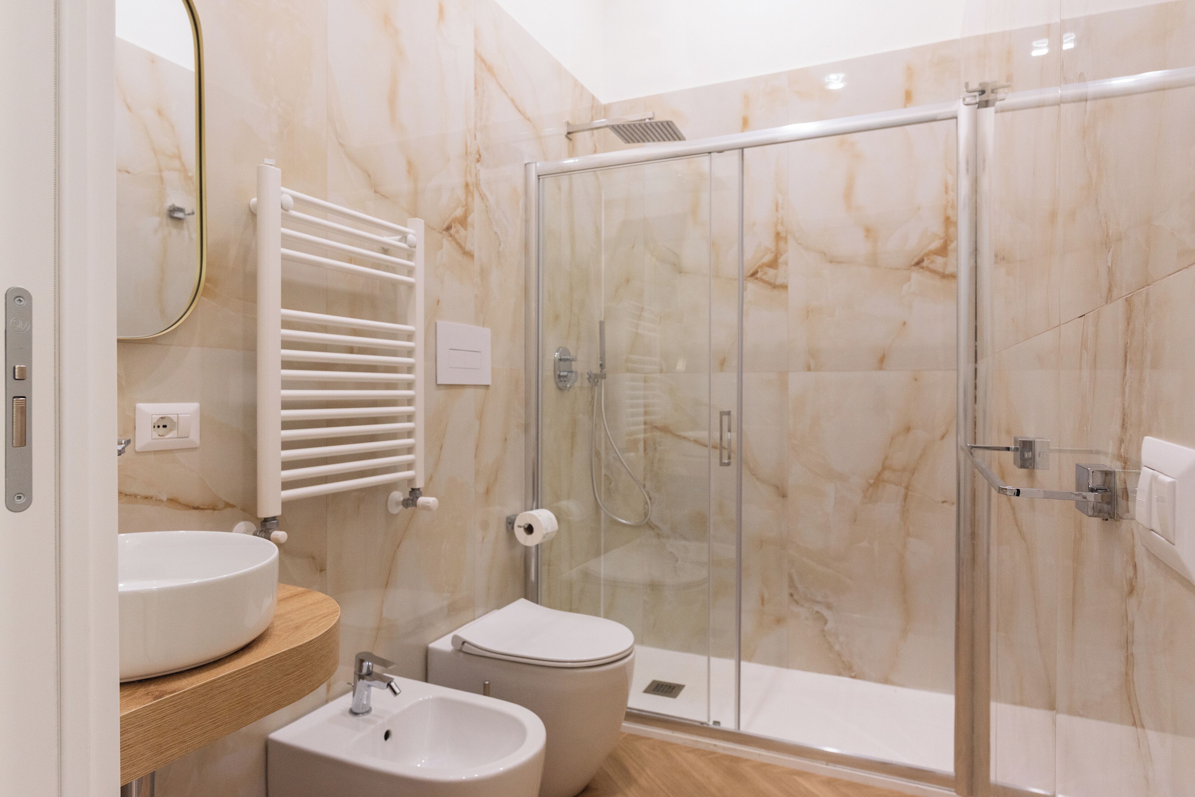A modern bathroom with a glass shower enclosure, a white sink, and a toilet.
