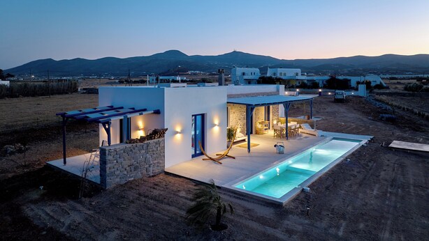 Une maison moderne dotée d’une piscine, de murs en pierre et d’un espace patio.
