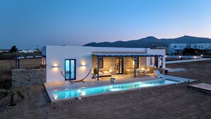 Une maison moderne dotée d’une piscine, de murs en pierre et offrant une vue sur les montagnes.