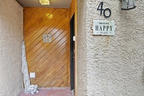 A wooden door with a star-shaped decoration, a house number sign, and a 'This is our happy place' sign on a textured wall. - Fresh & Modern Villa by the Sea Beach Club Getaway (Hilton Head Island)