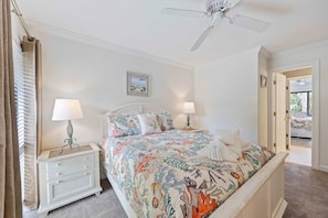 A bedroom with a bed, nightstands, a ceiling fan, and a view into an adjacent room. - Fresh & Modern Villa by the Sea Beach Club Getaway (Hilton Head Island)