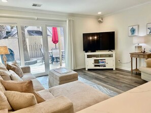 A living room with a sofa set, a flat-screen TV, and a sliding glass door leading to an outdoor area. - Fresh & Modern Villa by the Sea Beach Club Getaway (Hilton Head Island)