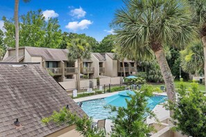 A residential area with a swimming pool surrounded by palm trees and a clear blue sky. - Fresh & Modern Villa by the Sea Beach Club Getaway (Hilton Head Island)