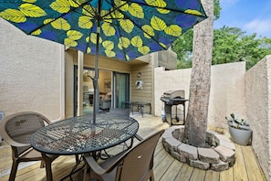 An outdoor patio with a round table, chairs, a grill, and a decorative umbrella. - Fresh & Modern Villa by the Sea Beach Club Getaway (Hilton Head Island)