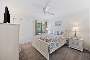 A bedroom with a bed, bedside tables, a ceiling fan, a window with curtains, and a door. - Fresh & Modern Villa by the Sea Beach Club Getaway (Hilton Head Island)