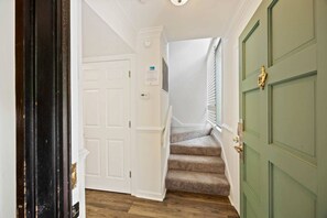 A staircase with carpeted steps leading to a door with a brass handle. - Fresh & Modern Villa by the Sea Beach Club Getaway (Hilton Head Island)