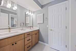 A bathroom with a double sink vanity, wooden cabinets, and a large mirror with lights. - Fresh & Modern Villa by the Sea Beach Club Getaway (Hilton Head Island)