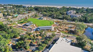 An aerial view of a coastal resort with a large green lawn, a swimming pool, and a marina. - Fresh & Modern Villa by the Sea Beach Club Getaway (Hilton Head Island)