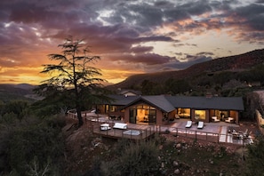 A modern house with a large deck, surrounded by natural landscape and mountains. - Best of Sedona Views, Cliffside Deck, Fitness/Yoga Room and More! (Sedona)