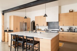 A modern kitchen with a large island, wooden cabinets, stainless steel appliances, and pendant lighting. - Best of Sedona Views, Cliffside Deck, Fitness/Yoga Room and More! (Sedona)