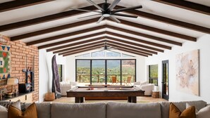 A spacious living area with a pool table, comfortable seating, and large windows offering a view of the outdoors. - Best of Sedona Views, Cliffside Deck, Fitness/Yoga Room and More! (Sedona)