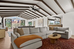 A modern living room with a sectional sofa, a coffee table, and a large window offering a view of a mountainous landscape. - Best of Sedona Views, Cliffside Deck, Fitness/Yoga Room and More! (Sedona)