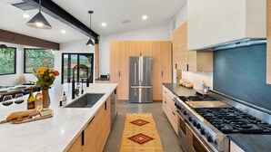A modern kitchen with a large island, stainless steel appliances, and a view of the outdoors. - Best of Sedona Views, Cliffside Deck, Fitness/Yoga Room and More! (Sedona)
