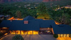 A modern house with a dark roof, surrounded by lush greenery and mountains in the background. - Best of Sedona Views, Cliffside Deck, Fitness/Yoga Room and More! (Sedona)
